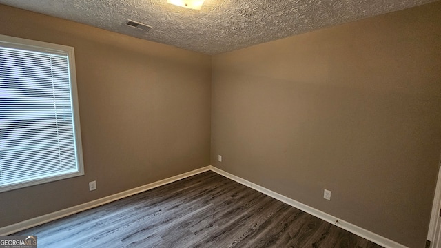 spare room with plenty of natural light, hardwood / wood-style floors, and a textured ceiling