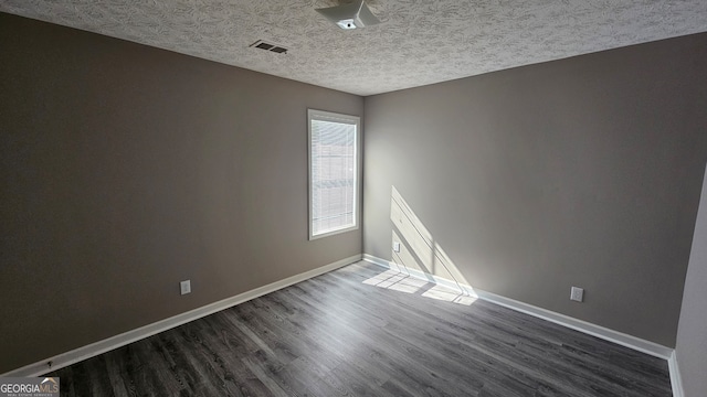 spare room featuring dark wood-type flooring and a textured ceiling