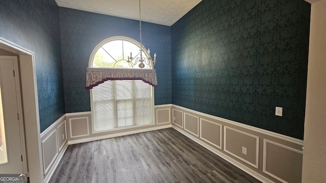 spare room with wood-type flooring and an inviting chandelier