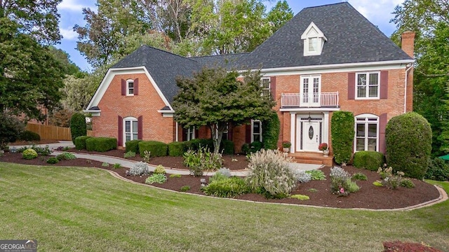 view of front of house featuring a balcony and a front lawn