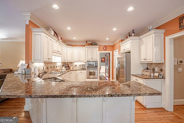 kitchen featuring light hardwood / wood-style floors, stainless steel appliances, kitchen peninsula, and a breakfast bar