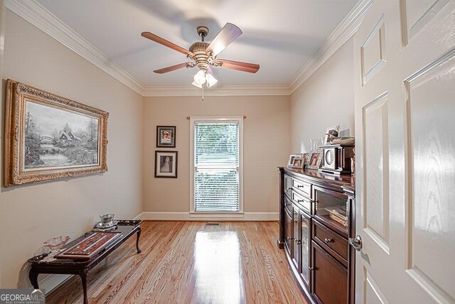 living area with ornamental molding, light wood-type flooring, and ceiling fan