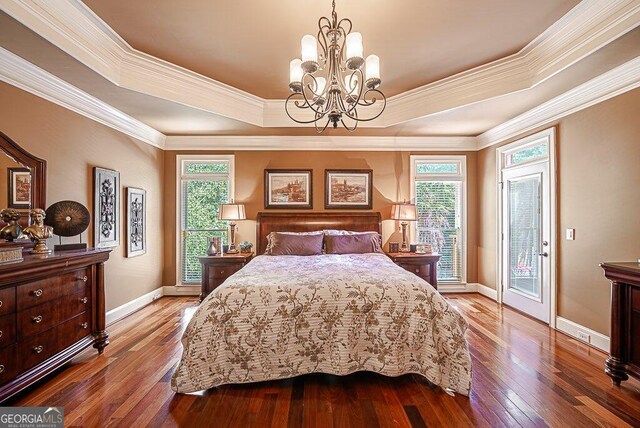 bedroom with a raised ceiling, crown molding, wood-type flooring, and access to outside