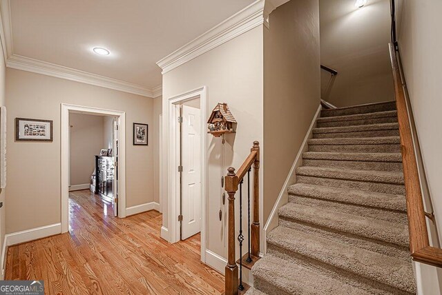 staircase featuring ornamental molding and wood-type flooring