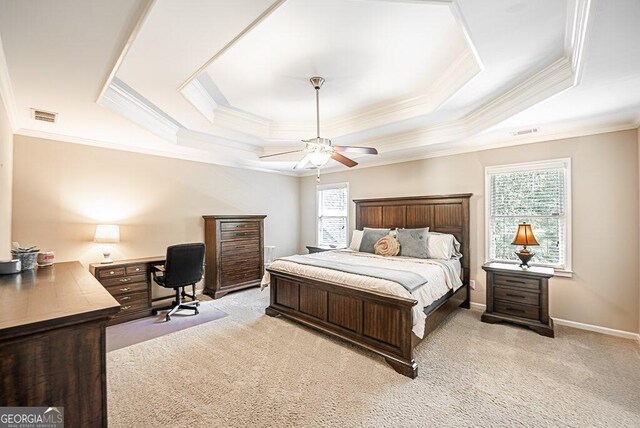 carpeted bedroom featuring ceiling fan, multiple windows, and a tray ceiling