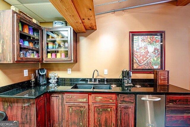 bar featuring dark stone countertops, a paneled ceiling, and sink