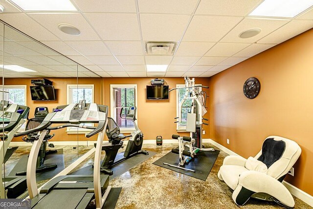 exercise area featuring a paneled ceiling, concrete floors, and a wealth of natural light