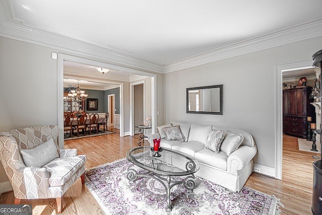 living room featuring a notable chandelier, crown molding, and light hardwood / wood-style floors