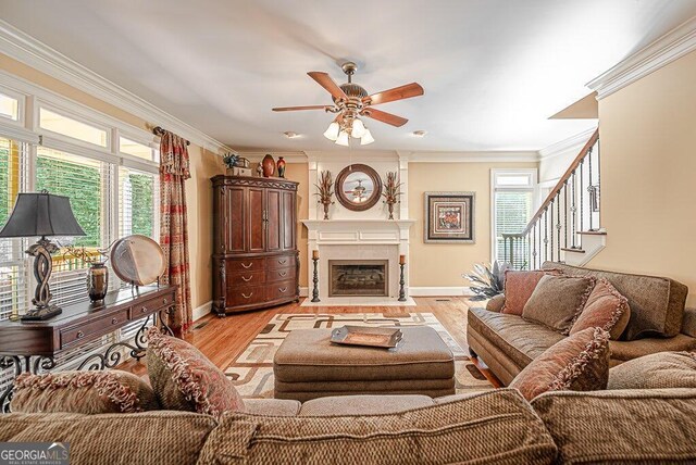 living room featuring ornamental molding, light hardwood / wood-style flooring, and ceiling fan