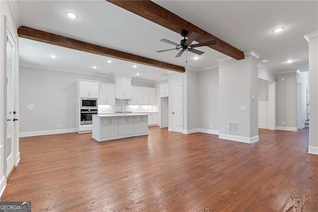 unfurnished living room featuring ceiling fan, beam ceiling, sink, and light hardwood / wood-style floors