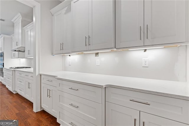 kitchen featuring dark wood-type flooring, stainless steel gas stovetop, and white cabinetry