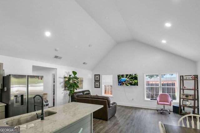 kitchen with light stone counters, sink, high vaulted ceiling, stainless steel refrigerator with ice dispenser, and dark hardwood / wood-style floors