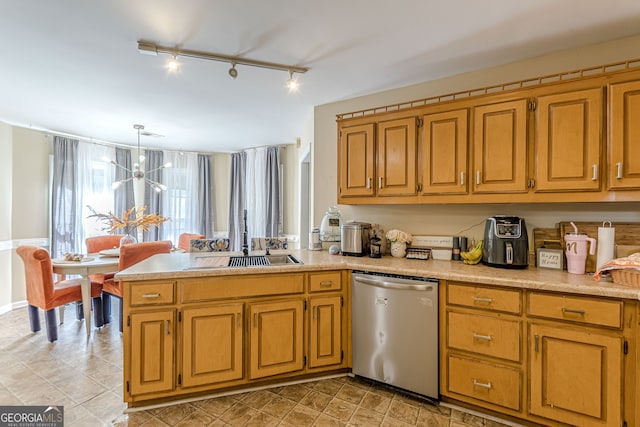 kitchen featuring kitchen peninsula, rail lighting, decorative light fixtures, stainless steel dishwasher, and a chandelier