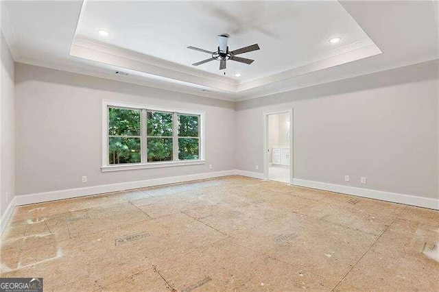 empty room featuring ceiling fan, a raised ceiling, and crown molding