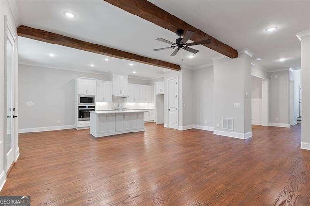 unfurnished living room with ceiling fan, beamed ceiling, ornamental molding, sink, and hardwood / wood-style flooring