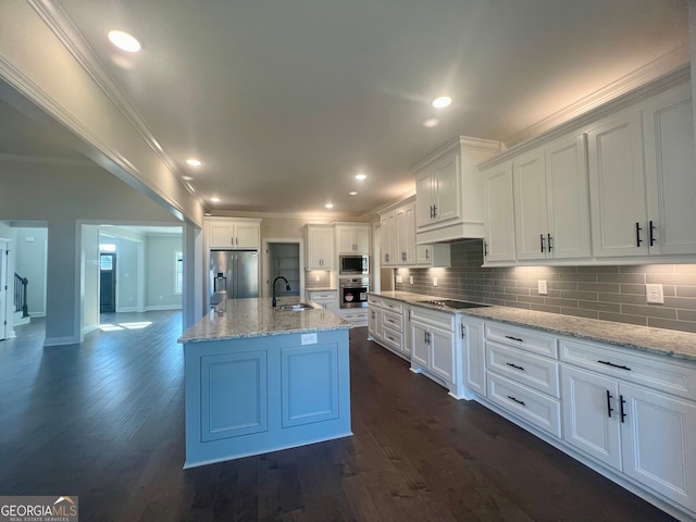 kitchen with dark hardwood / wood-style floors, stainless steel appliances, crown molding, white cabinetry, and a center island with sink