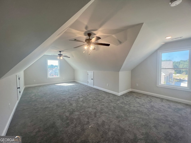 additional living space with ceiling fan, dark colored carpet, and vaulted ceiling