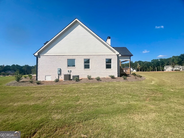 view of side of home featuring central air condition unit and a yard