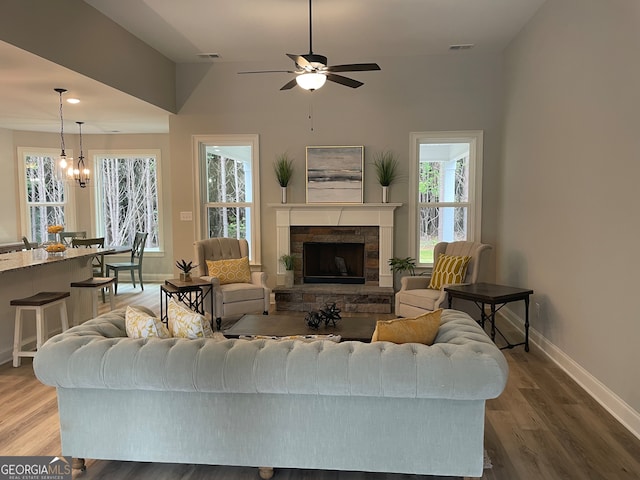 living room with ceiling fan with notable chandelier, hardwood / wood-style flooring, and a fireplace