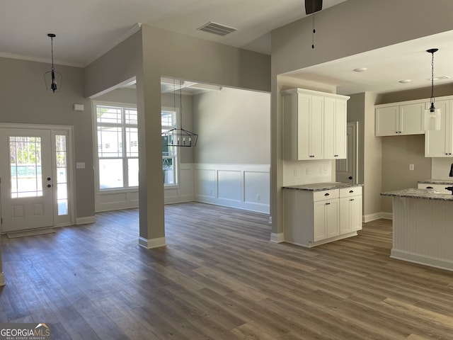 kitchen with white cabinets, dark stone counters, dark hardwood / wood-style floors, and ornamental molding