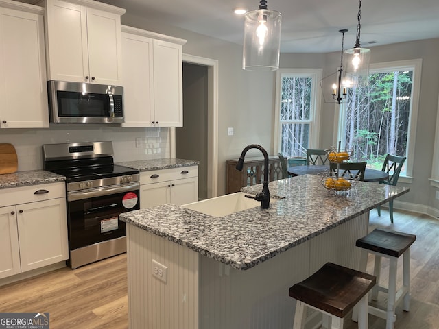 kitchen with light wood-type flooring, dark stone countertops, white cabinetry, and stainless steel appliances