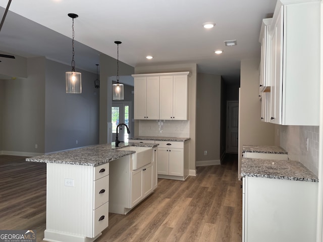 kitchen with a kitchen island with sink, sink, and white cabinetry