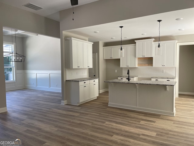 kitchen with white cabinets, an island with sink, and dark wood-type flooring