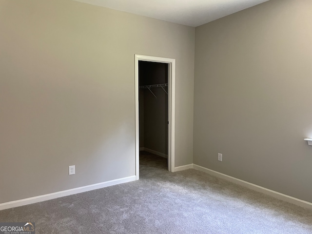 unfurnished bedroom with a closet, carpet flooring, and a walk in closet