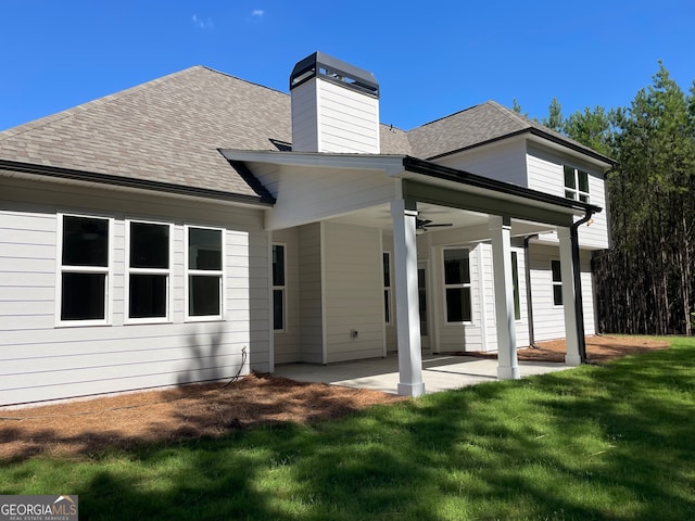 back of property with ceiling fan, a lawn, and a patio area