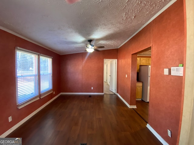 empty room featuring ornamental molding, ceiling fan, dark wood-type flooring, and a textured ceiling