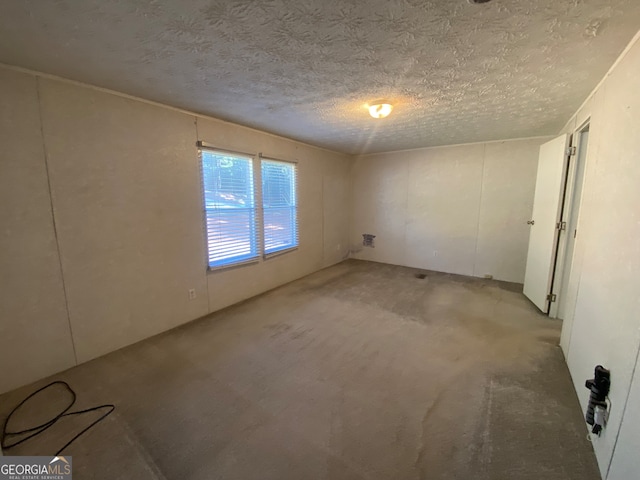 spare room featuring light colored carpet and a textured ceiling