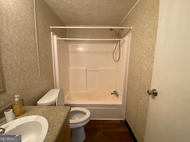 full bathroom with vanity, wood-type flooring, a textured ceiling, shower / tub combination, and toilet