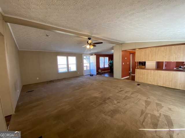 unfurnished living room featuring lofted ceiling, ceiling fan, carpet, and a textured ceiling