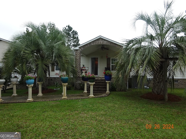 view of front of property with ceiling fan and a front yard