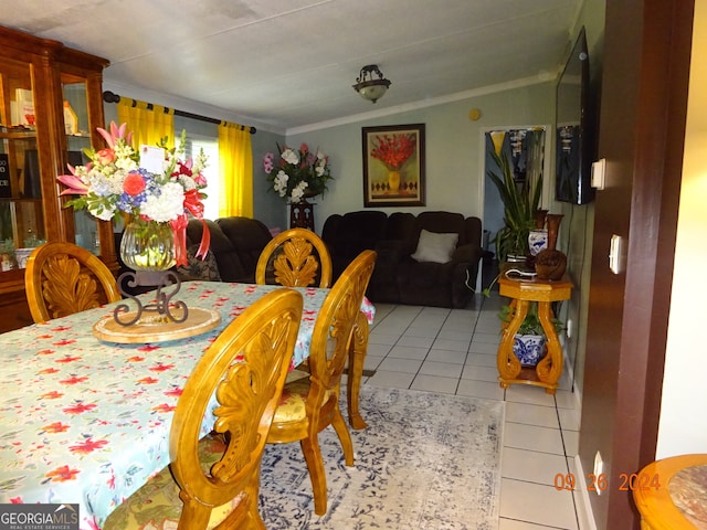 tiled dining space with lofted ceiling and ornamental molding