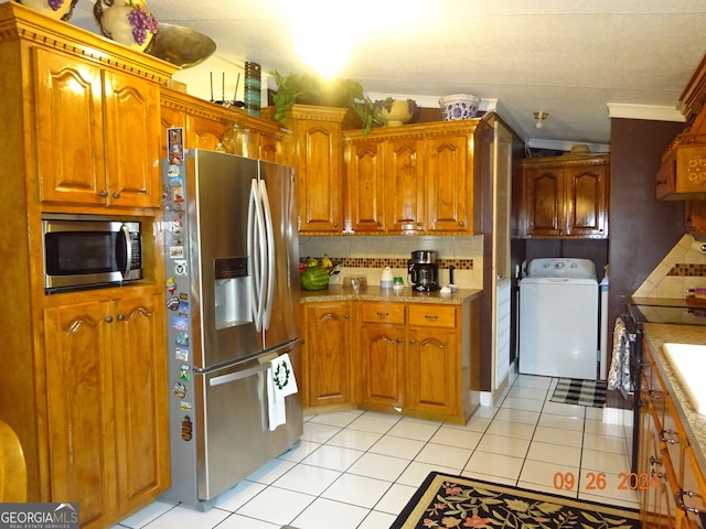 kitchen featuring washer / clothes dryer, stainless steel appliances, light tile patterned floors, and tasteful backsplash