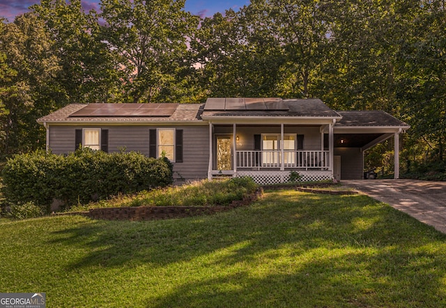 view of front of property with a porch, a carport, a lawn, and solar panels