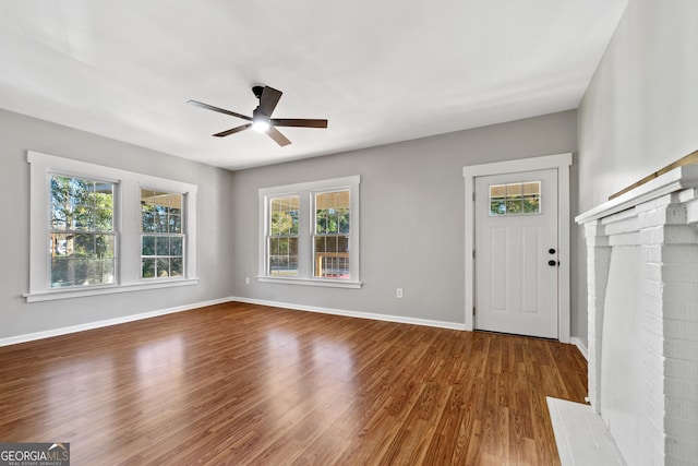 foyer featuring wood-type flooring, a brick fireplace, and ceiling fan