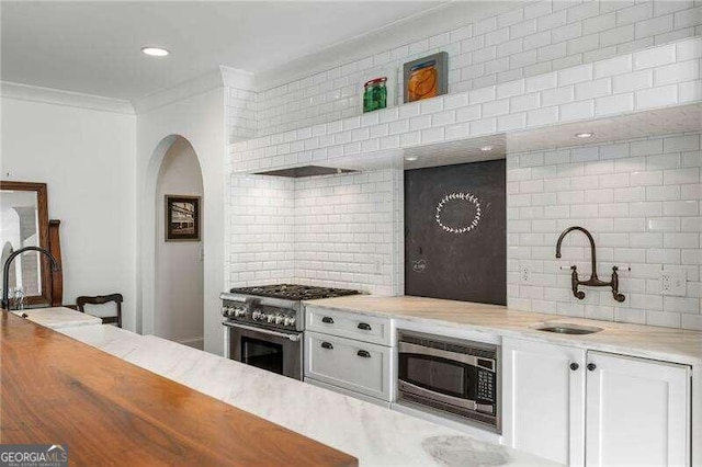 kitchen featuring appliances with stainless steel finishes, sink, tasteful backsplash, and white cabinetry