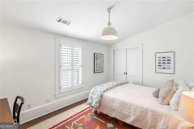 bedroom with hardwood / wood-style flooring, a closet, and lofted ceiling