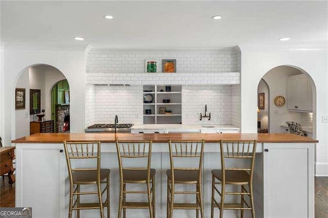 bar with backsplash, dark hardwood / wood-style floors, and ornamental molding