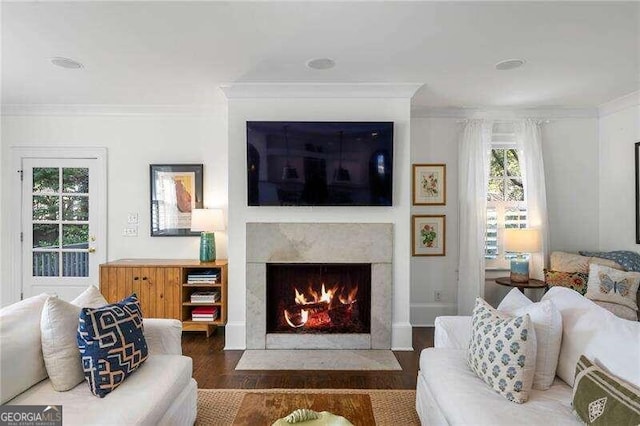 living room with crown molding, dark wood-type flooring, and a high end fireplace