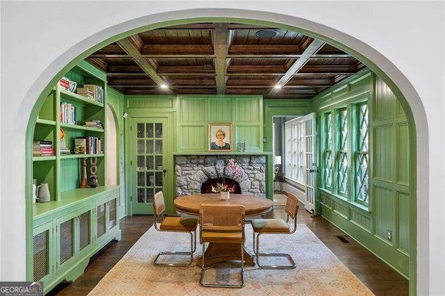 interior space with coffered ceiling, beam ceiling, a stone fireplace, and wood ceiling