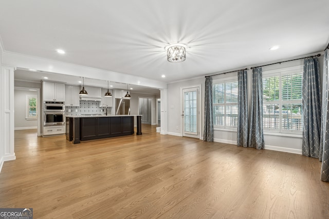 unfurnished living room with ornamental molding and light hardwood / wood-style floors