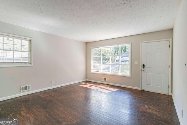 empty room featuring dark wood-type flooring and a textured ceiling