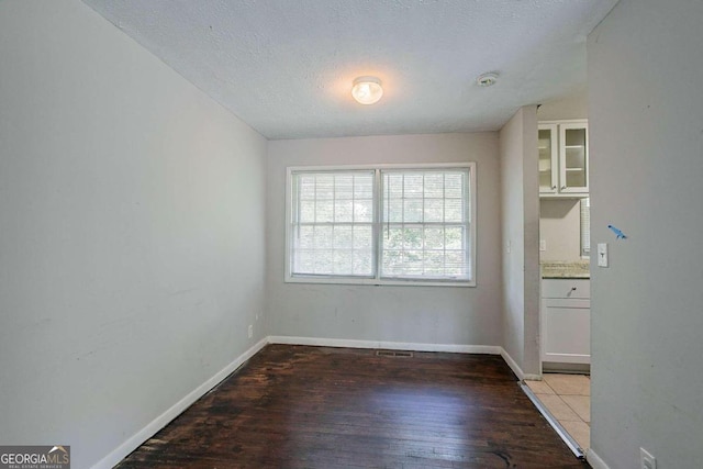 unfurnished room with light wood-type flooring and a textured ceiling