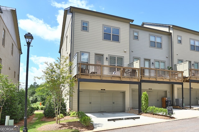 rear view of house featuring central AC unit, a balcony, and a garage