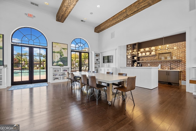 dining room with a high ceiling, built in shelves, beamed ceiling, dark wood-type flooring, and french doors