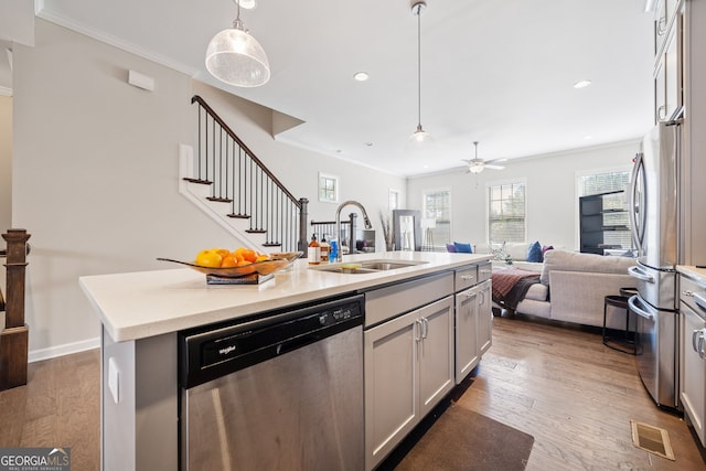 kitchen with a center island with sink, stainless steel appliances, sink, and hardwood / wood-style flooring