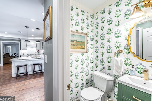 bathroom featuring hardwood / wood-style flooring, vanity, toilet, and crown molding